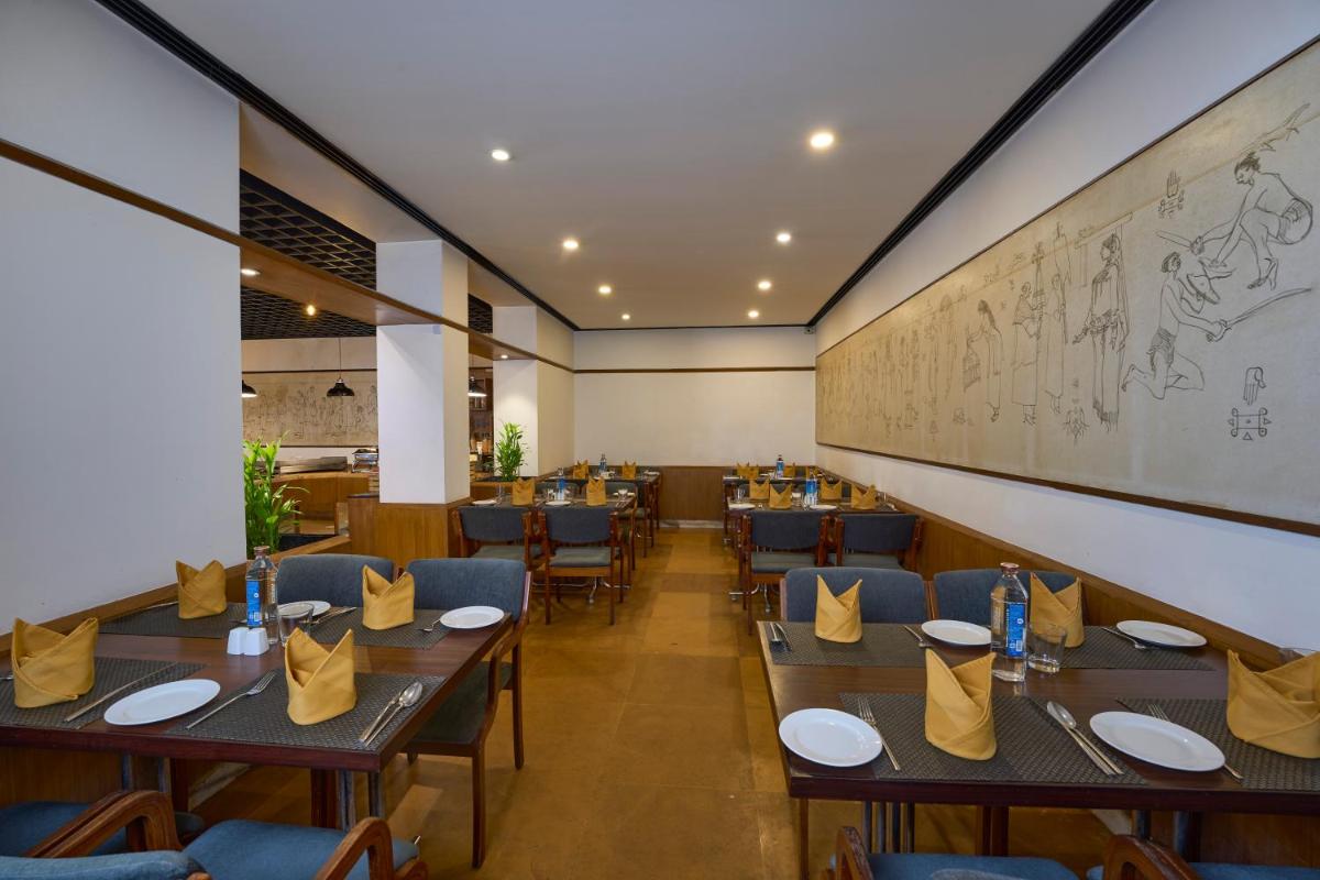 a restaurant with tables and chairs and a chalkboard at Casino Hotel - CGH Earth, Cochin in Cochin
