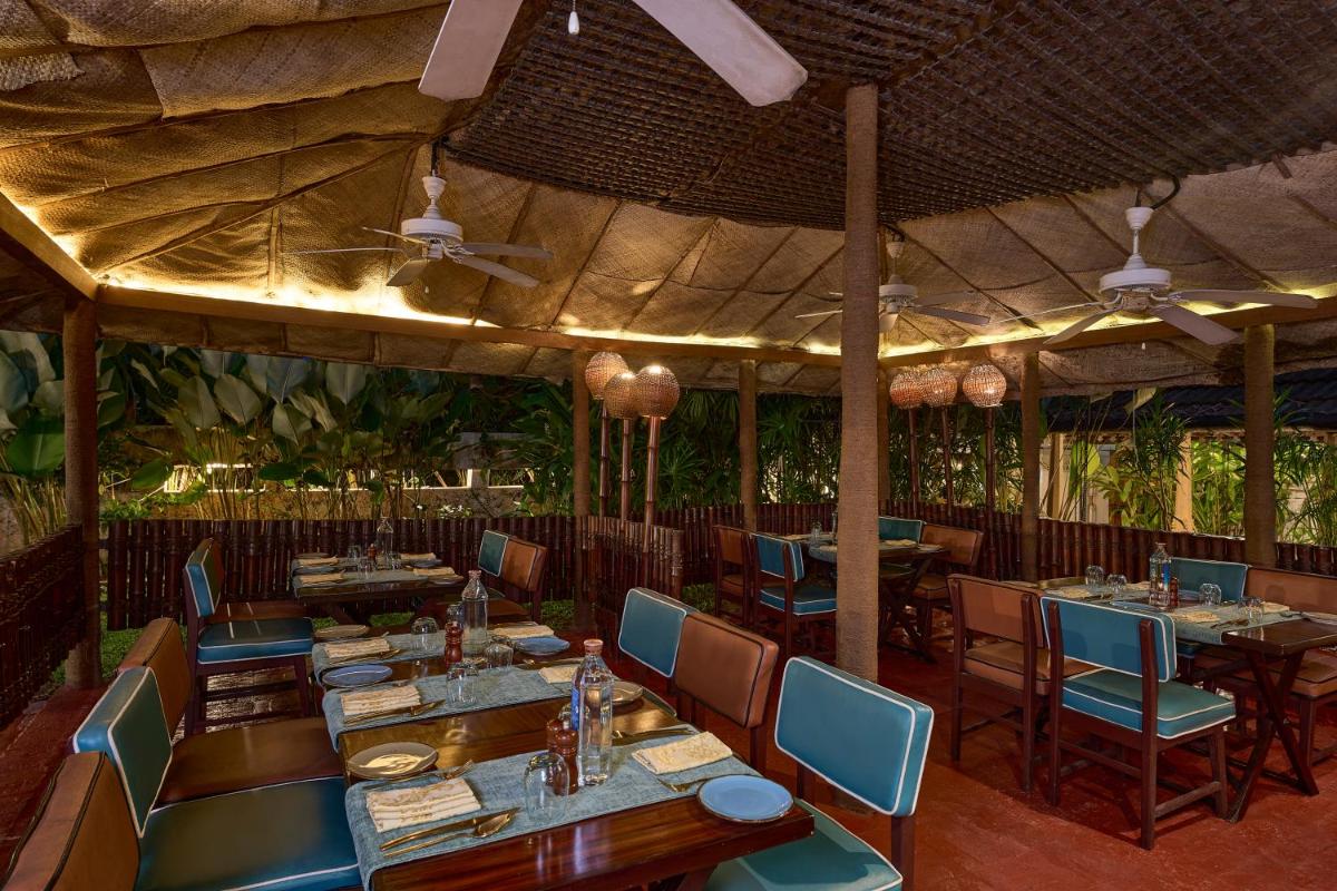 a restaurant with wooden tables and blue chairs at Casino Hotel - CGH Earth, Cochin in Cochin