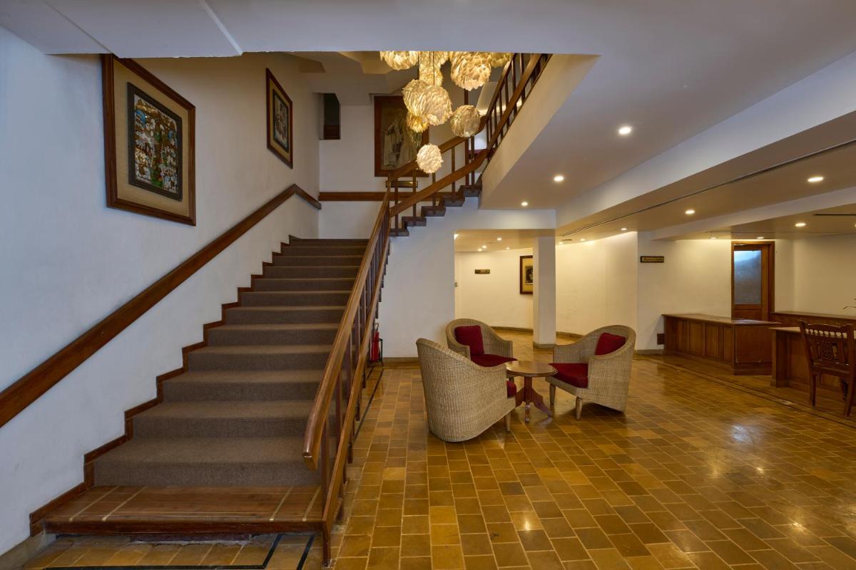 a staircase with chairs and a table in a room at Casino Hotel - CGH Earth, Cochin in Cochin
