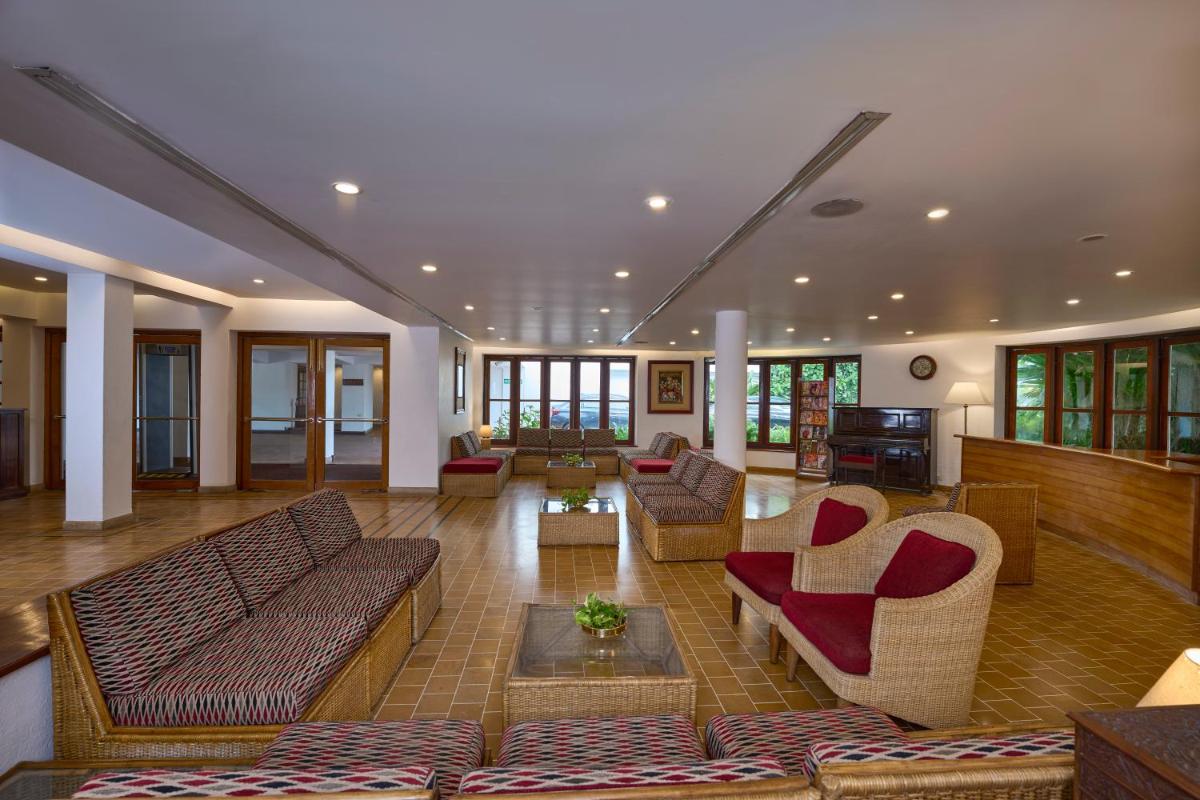 a living room with couches and chairs in a building at Casino Hotel - CGH Earth, Cochin in Cochin