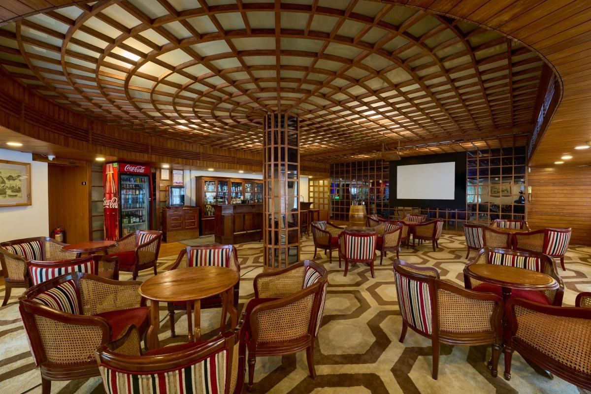 a restaurant with wooden tables and chairs and a screen at Casino Hotel - CGH Earth, Cochin in Cochin