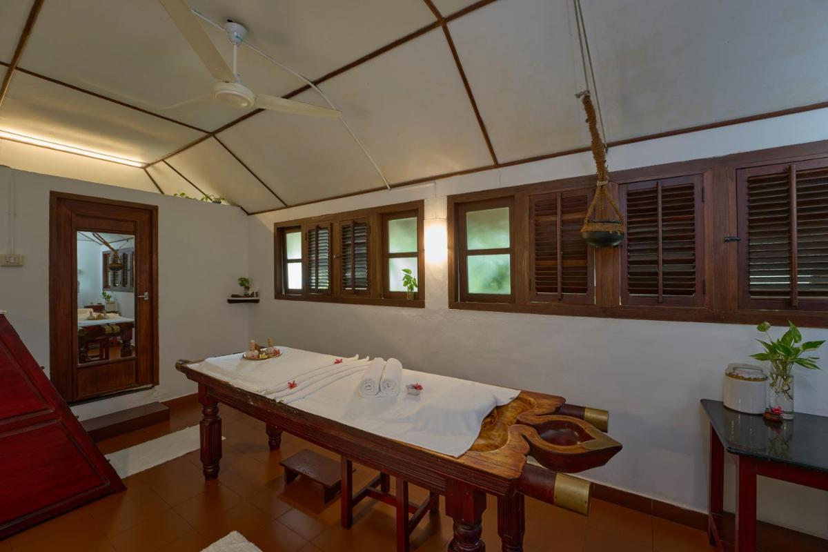 a living room with a table and a ceiling at Casino Hotel - CGH Earth, Cochin in Cochin