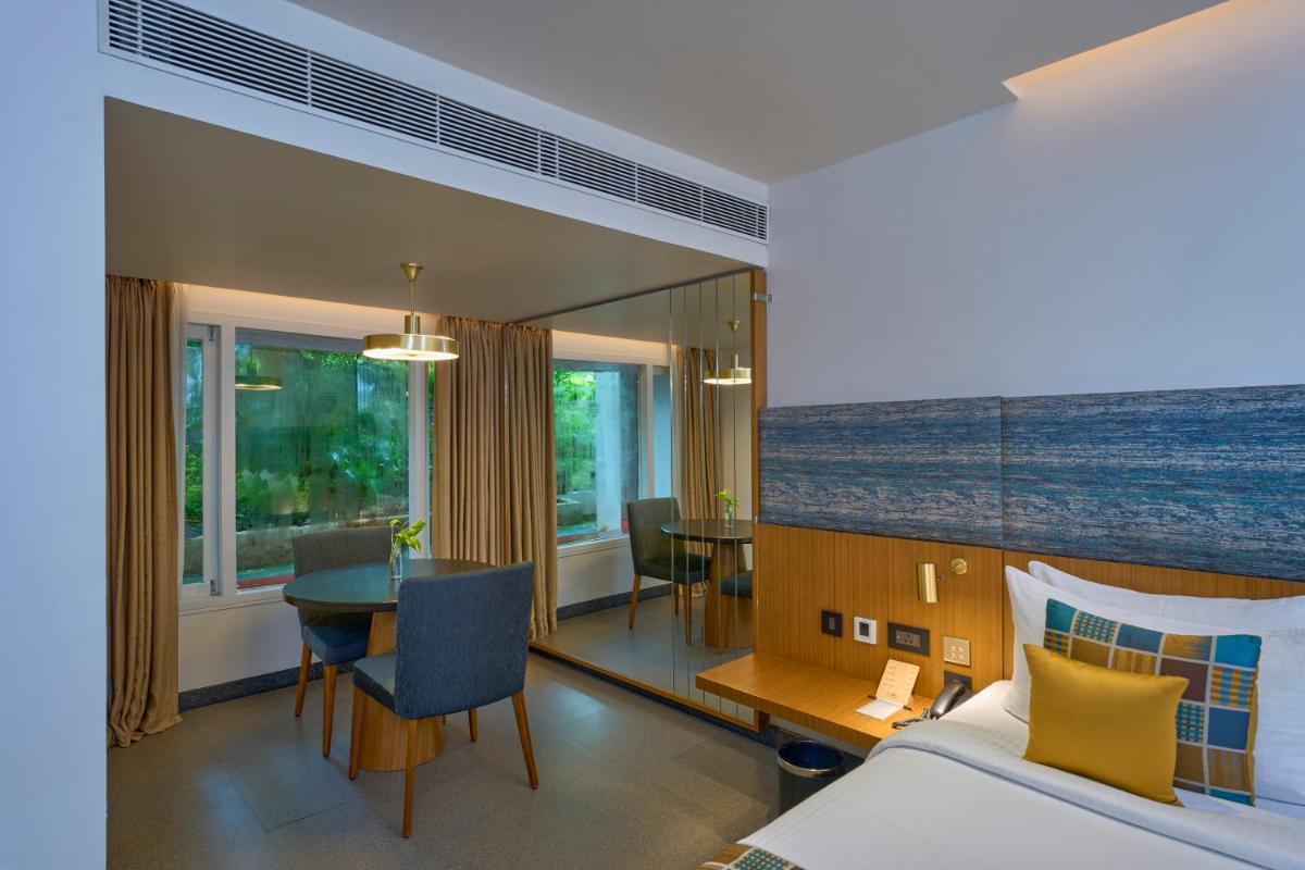 a bedroom with a bed and a table and a dining room at Casino Hotel - CGH Earth, Cochin in Cochin