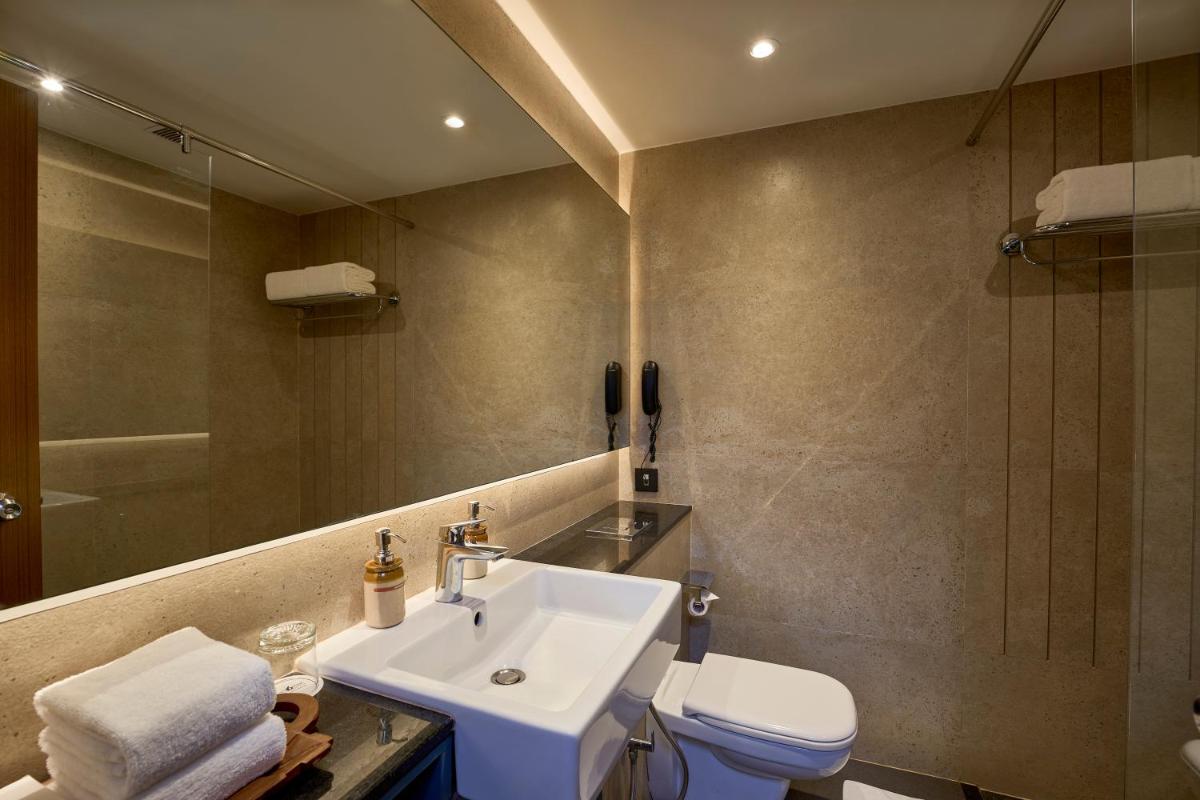 a bathroom with a sink and a toilet and a mirror at Casino Hotel - CGH Earth, Cochin in Cochin