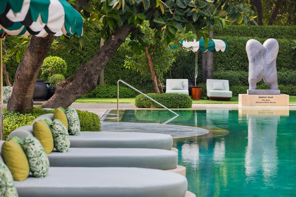 a resort pool with chairs and a statue in the background at Shangri-La Eros New Delhi in New Delhi a resort pool with chairs and a statue in the background at Shangri-La Eros New Delhi in New Delhi