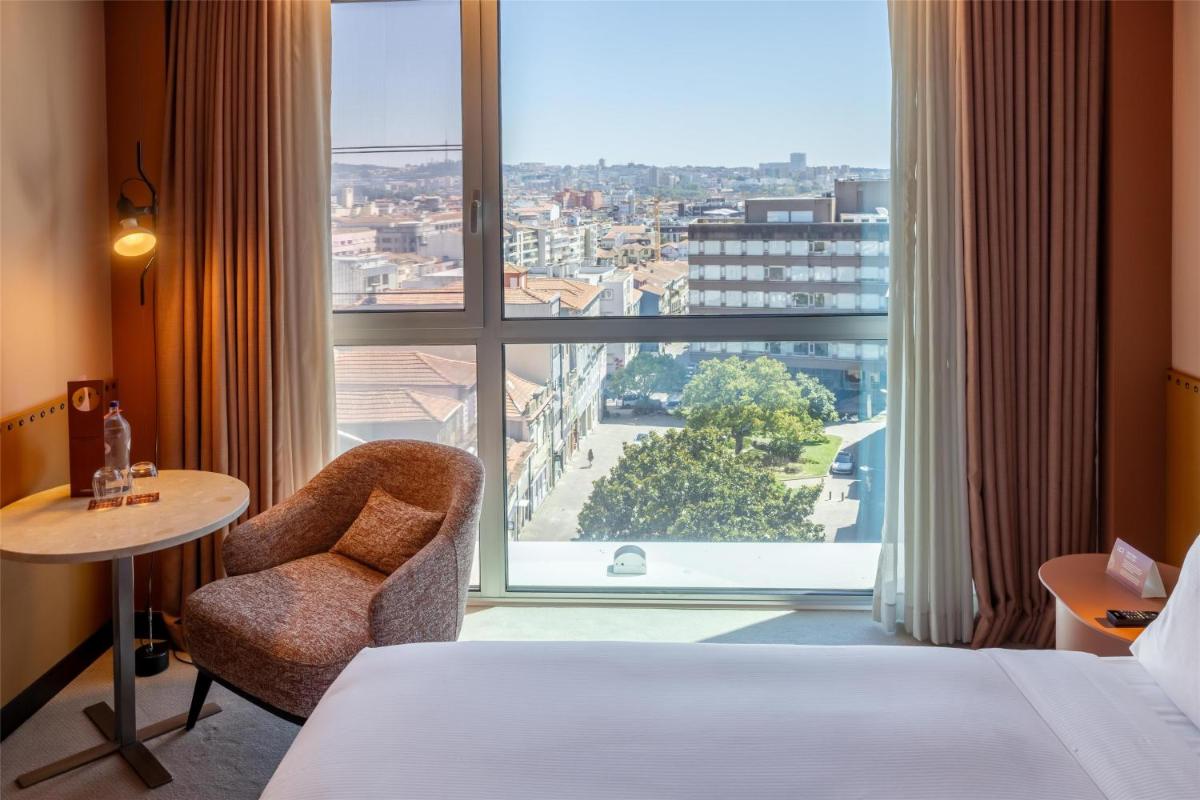 um quarto de hotel com uma cama e uma janela grande em Cenica Porto Hotel, Curio Collection By Hilton no Porto