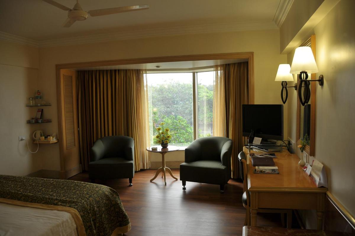 a hotel room with a bed and a desk with a computer at Ramada Plaza By Wyndham Palm Grove in Mumbai