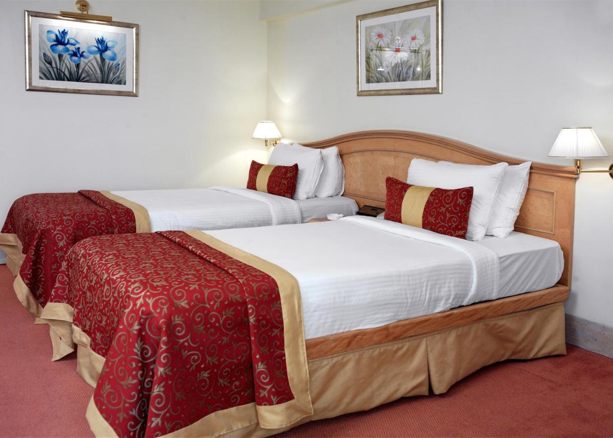 two beds in a hotel room with red and white sheets at Ramada Plaza By Wyndham Palm Grove in Mumbai