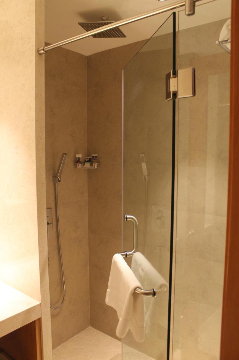 a shower with a glass door and a towel at Mercure Hyderabad KCP Banjara Hills, An Accor Hotel in Hyderabad