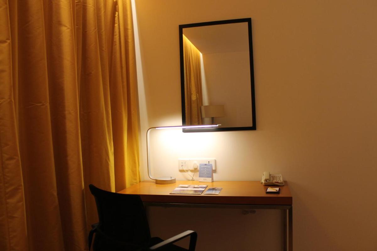 a room with a desk with a lamp and a mirror at Mercure Hyderabad KCP Banjara Hills, An Accor Hotel in Hyderabad