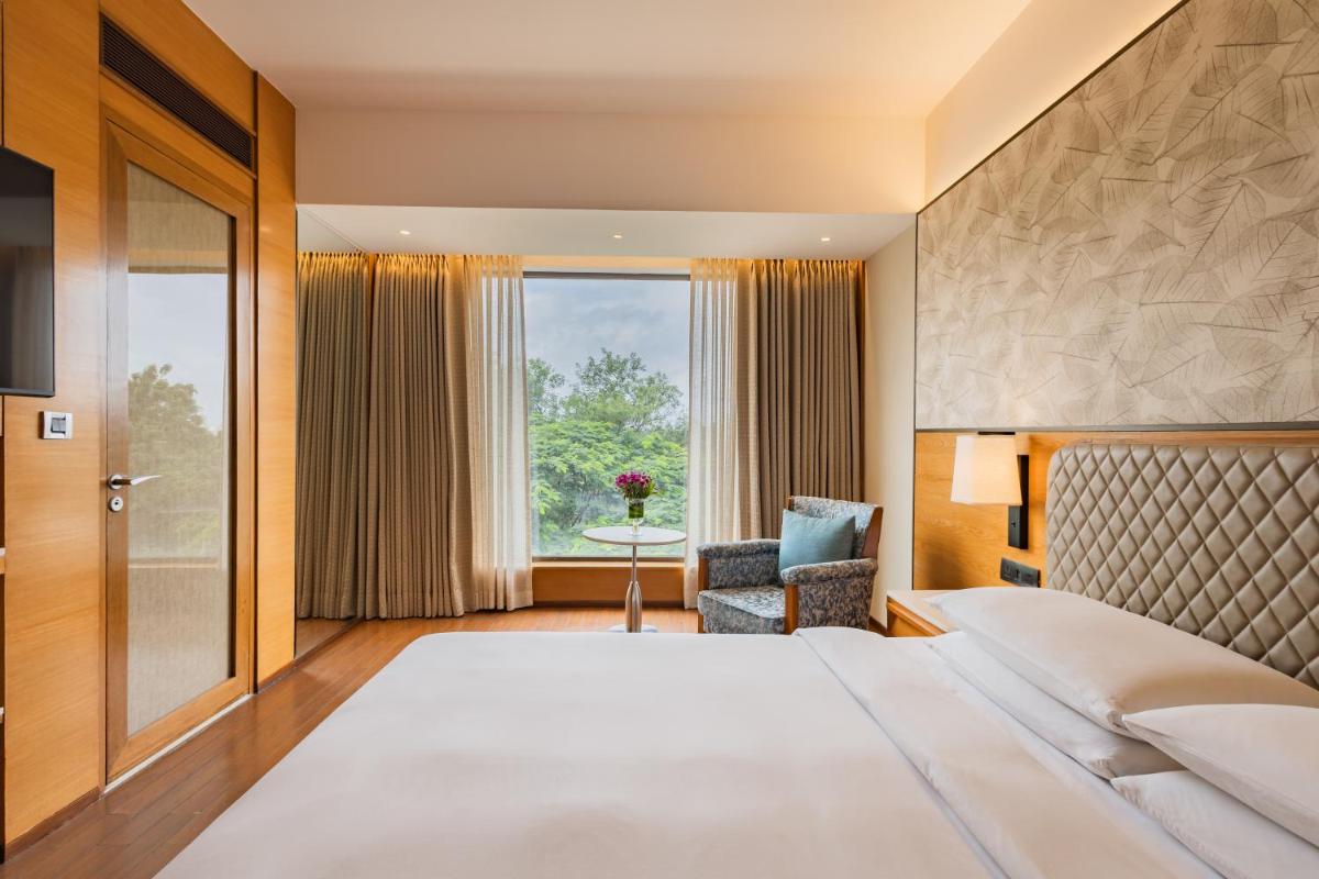 a hotel room with a large bed and a window at Hyatt Pune in Pune