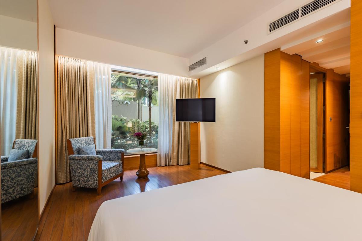 a hotel room with a bed and two chairs and a television at Hyatt Pune in Pune