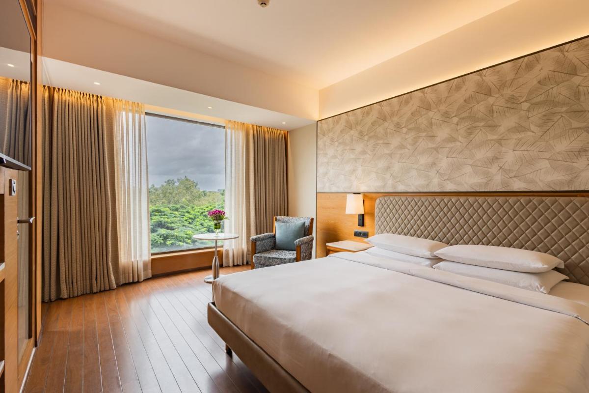 a hotel room with a large bed and a window at Hyatt Pune in Pune