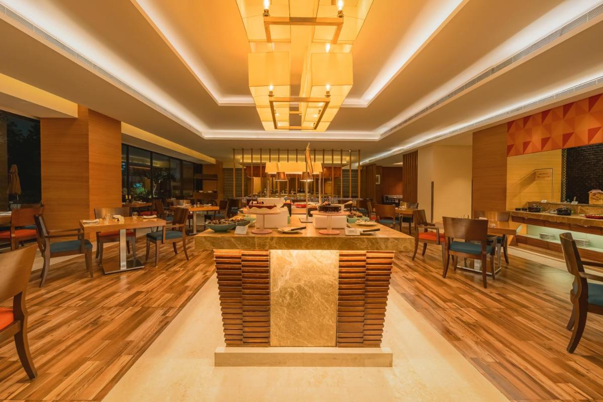 a restaurant with wooden floors and tables and chairs at Hyatt Pune in Pune