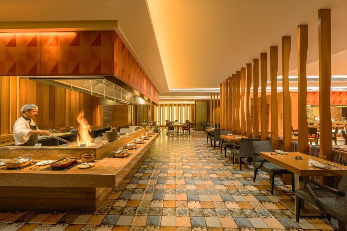 a restaurant with a chef preparing food in a kitchen at Hyatt Pune in Pune