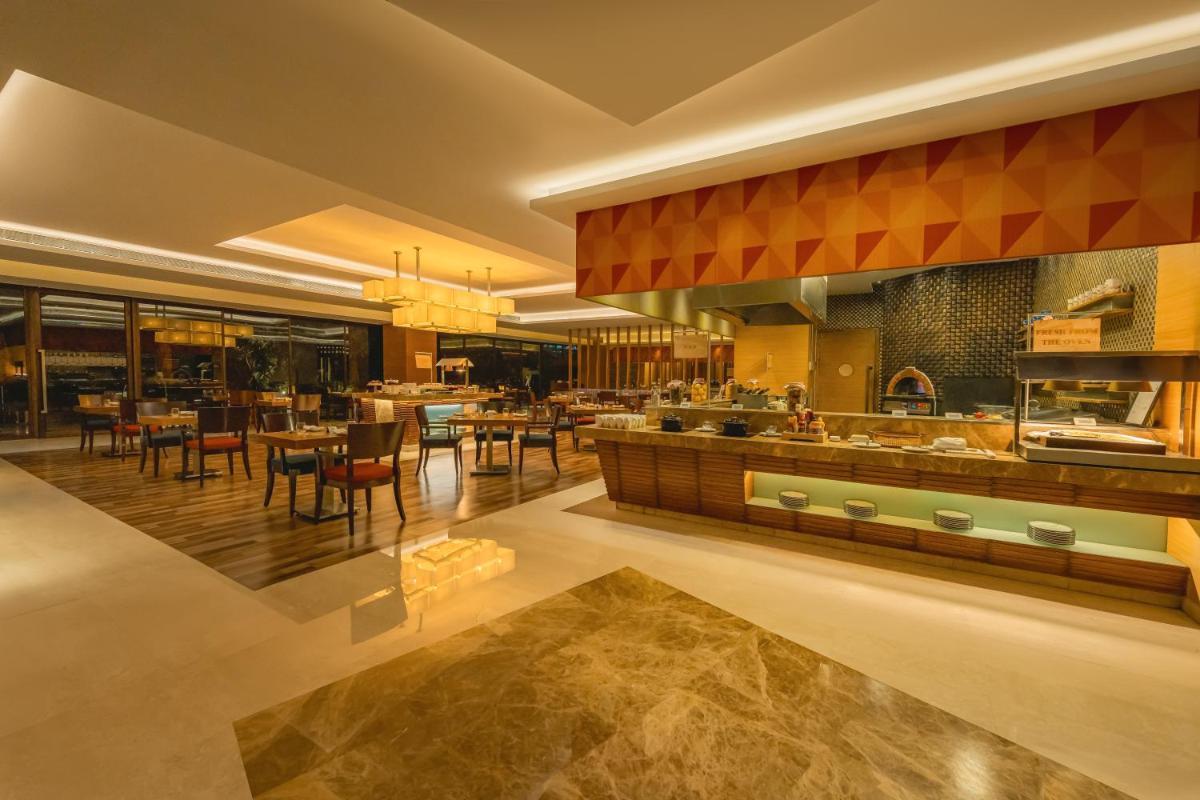 a kitchen and dining room with tables and chairs at Hyatt Pune in Pune