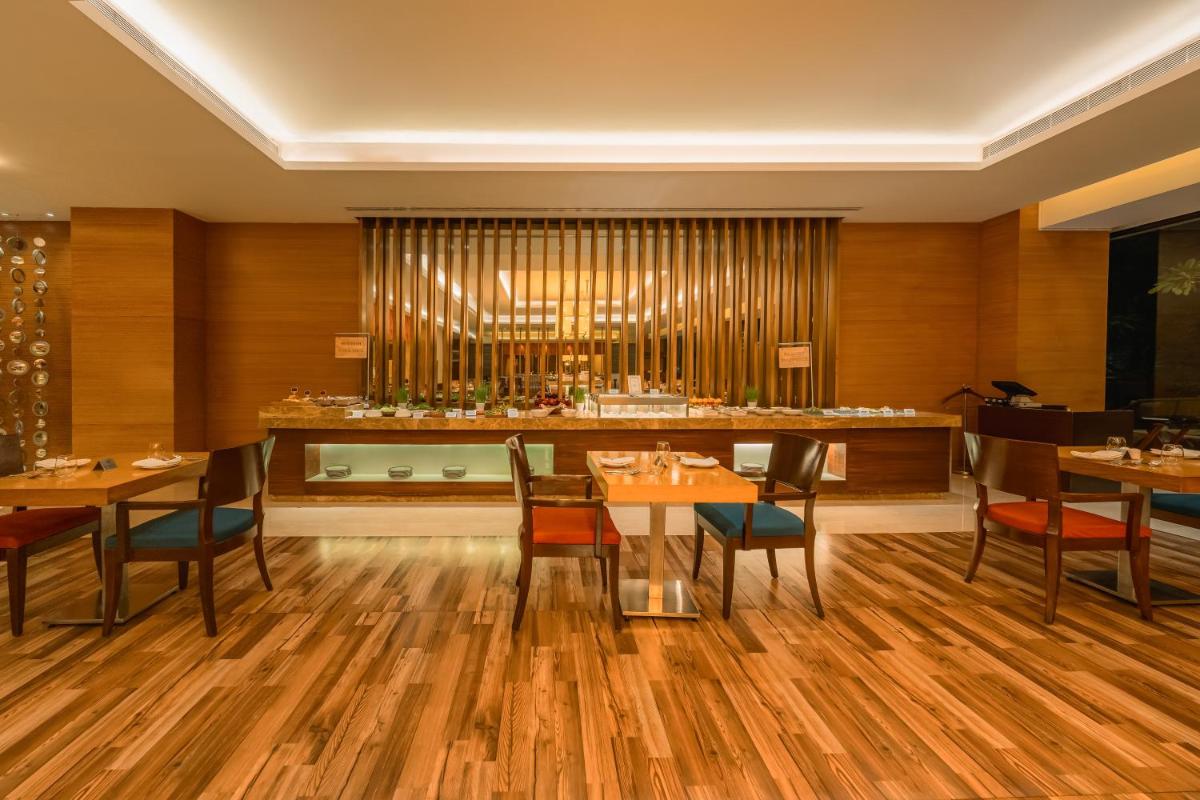 a restaurant with tables and chairs and a bar at Hyatt Pune in Pune