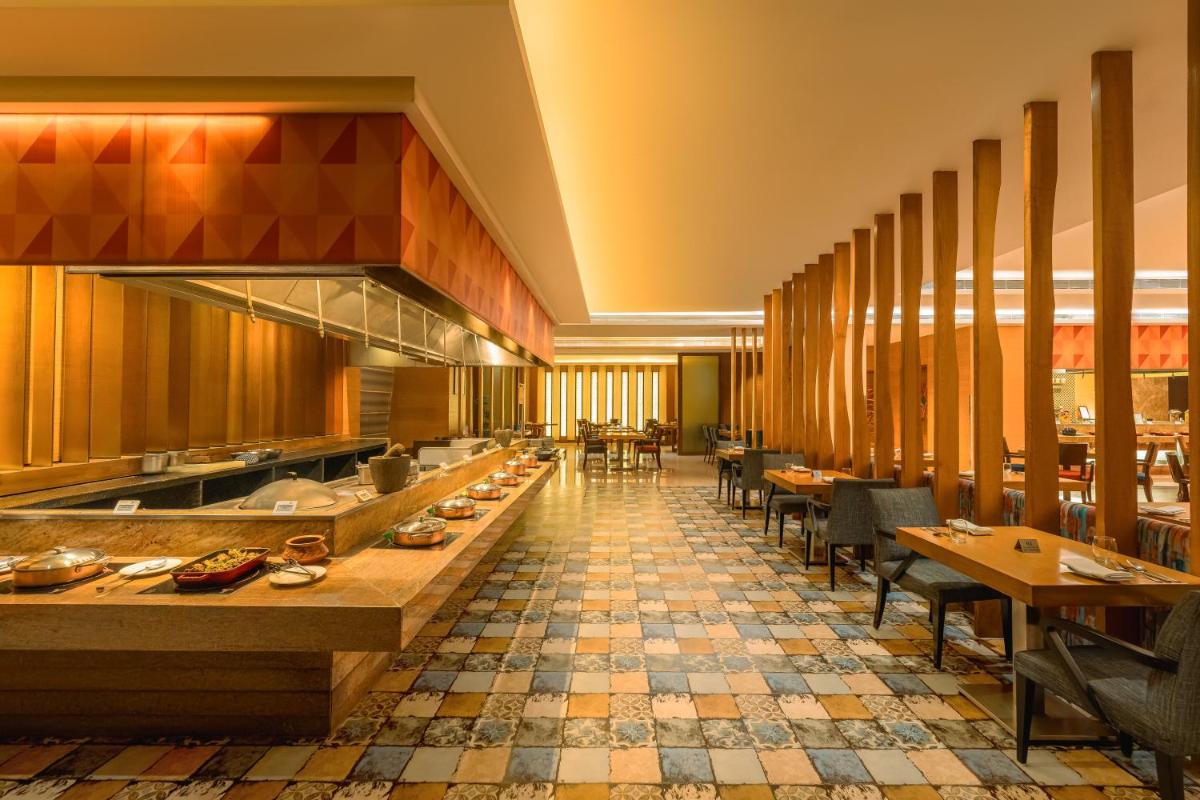 a restaurant with tables and chairs in a room at Hyatt Pune in Pune