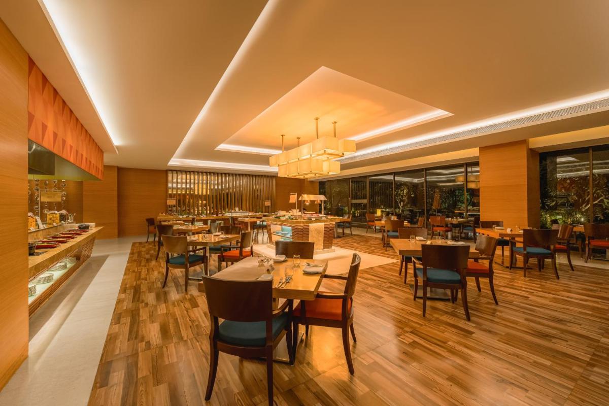 a restaurant with tables and chairs in a room at Hyatt Pune in Pune