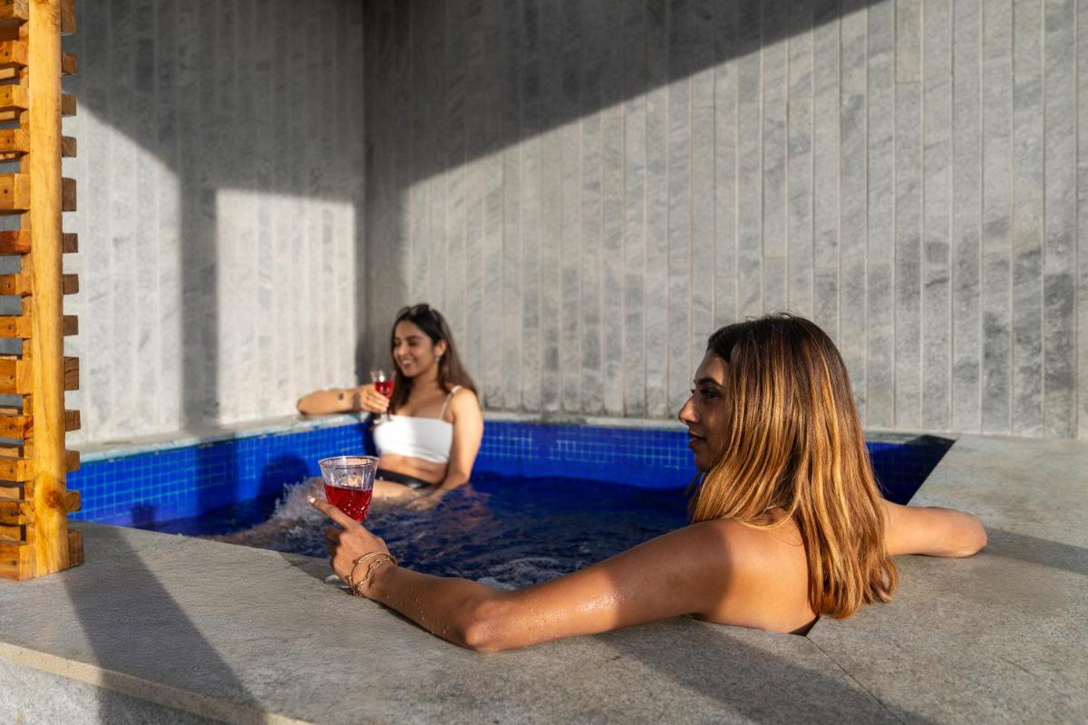 two women in a hot tub with a glass of wine at WelcomHeritage Ayatana Ooty in Ooty
