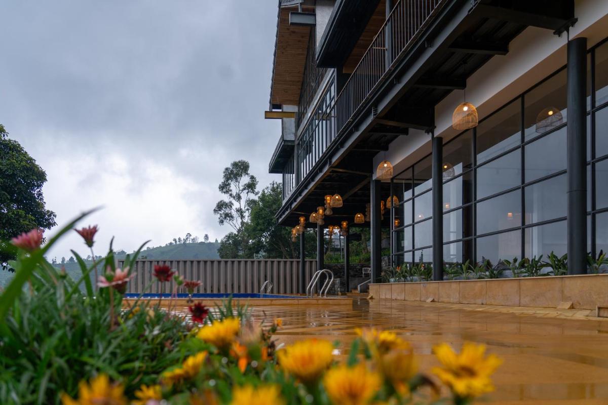 a building with windows and flowers in the foreground at WelcomHeritage Ayatana Ooty in Ooty