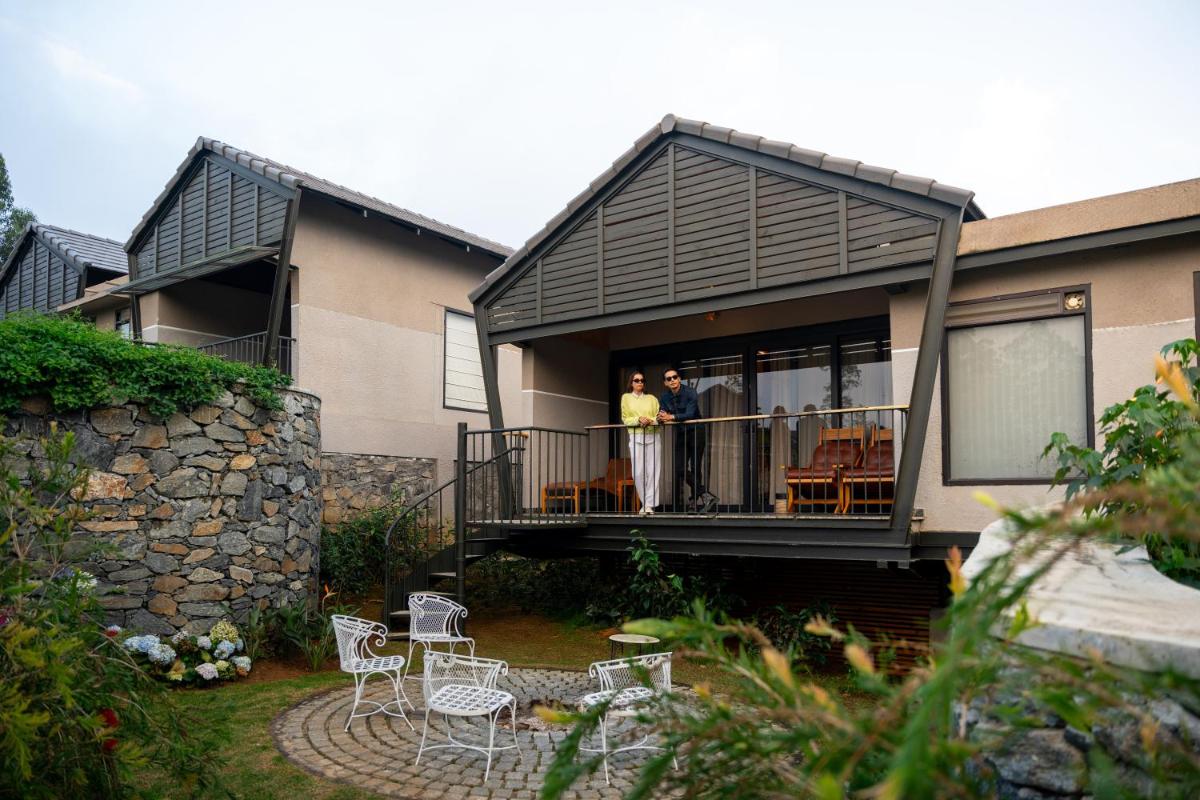 two people standing on the balcony of a house at WelcomHeritage Ayatana Ooty in Ooty