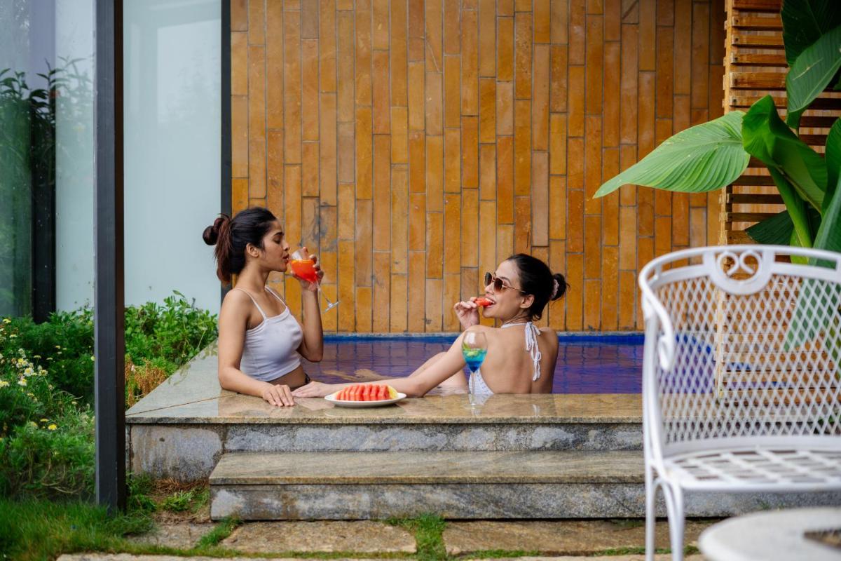 two women sitting on a porch eating watermelon at WelcomHeritage Ayatana Ooty in Ooty