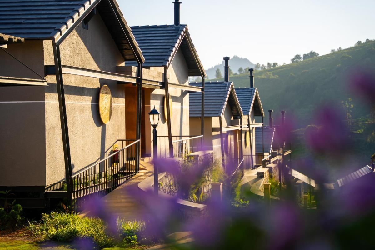 a row of houses with purple flowers in the foreground at WelcomHeritage Ayatana Ooty in Ooty