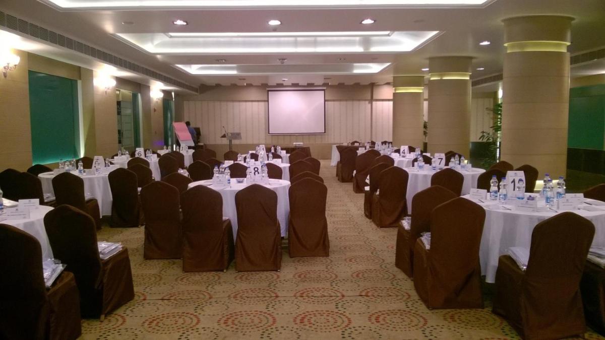 a banquet hall with white tables and chairs and a screen at Fortune JP Palace, Mysore - Member ITC Hotels' Group in Mysore