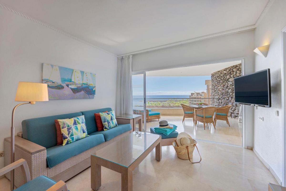 Una sala de estar con un sofá azul y una mesa. en Anfi del Mar 2, en La Playa de Arguineguín