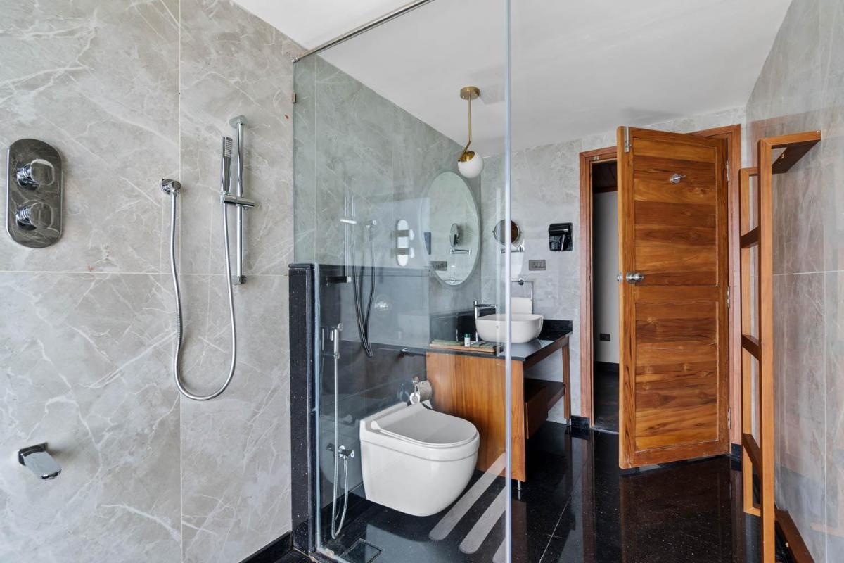 a bathroom with a toilet and a glass shower at WelcomHeritage Ayatana Ooty in Ooty