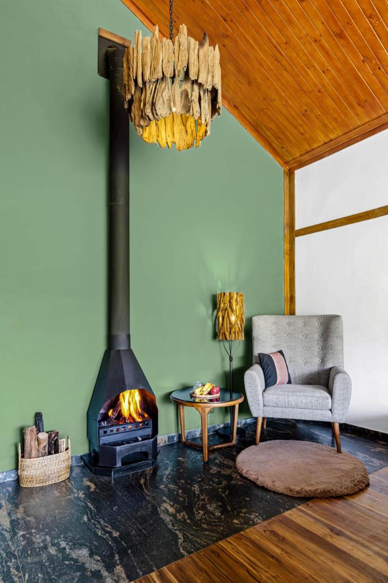 a living room with a fireplace and a couch and a chair at WelcomHeritage Ayatana Ooty in Ooty