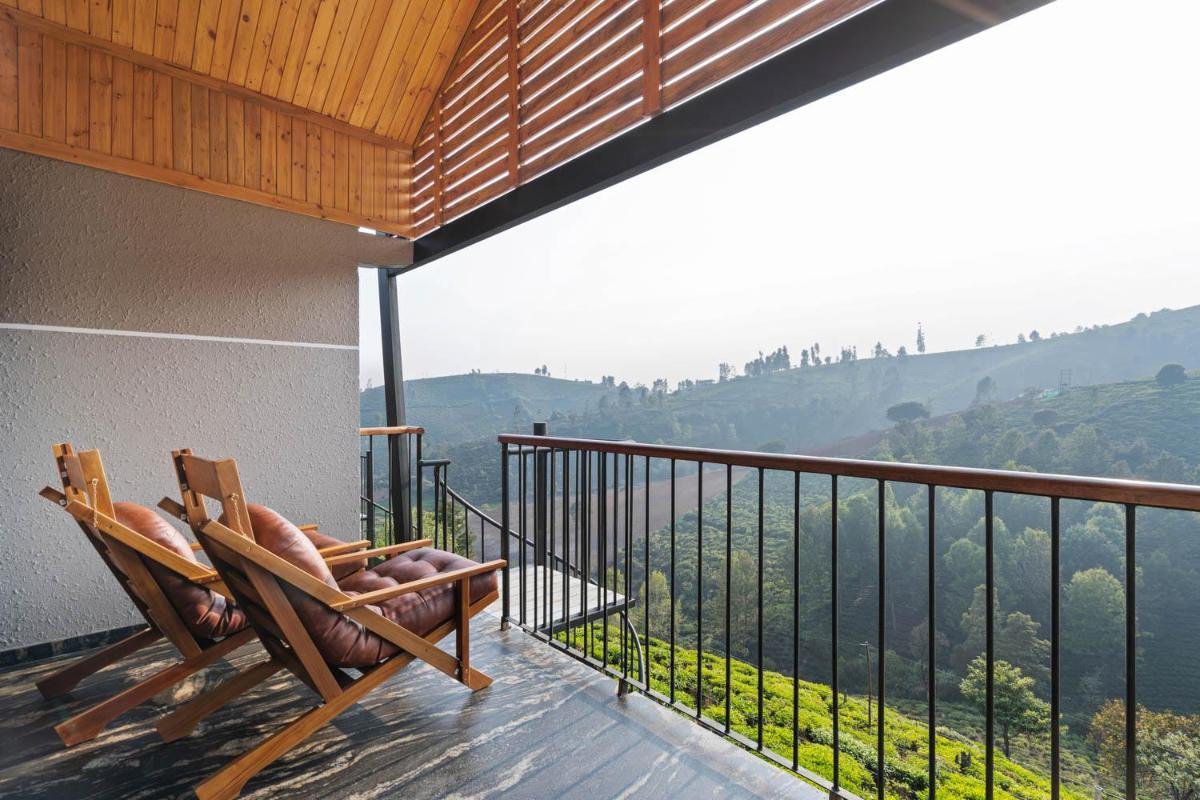 a wooden chair sitting on a balcony with a view at WelcomHeritage Ayatana Ooty in Ooty