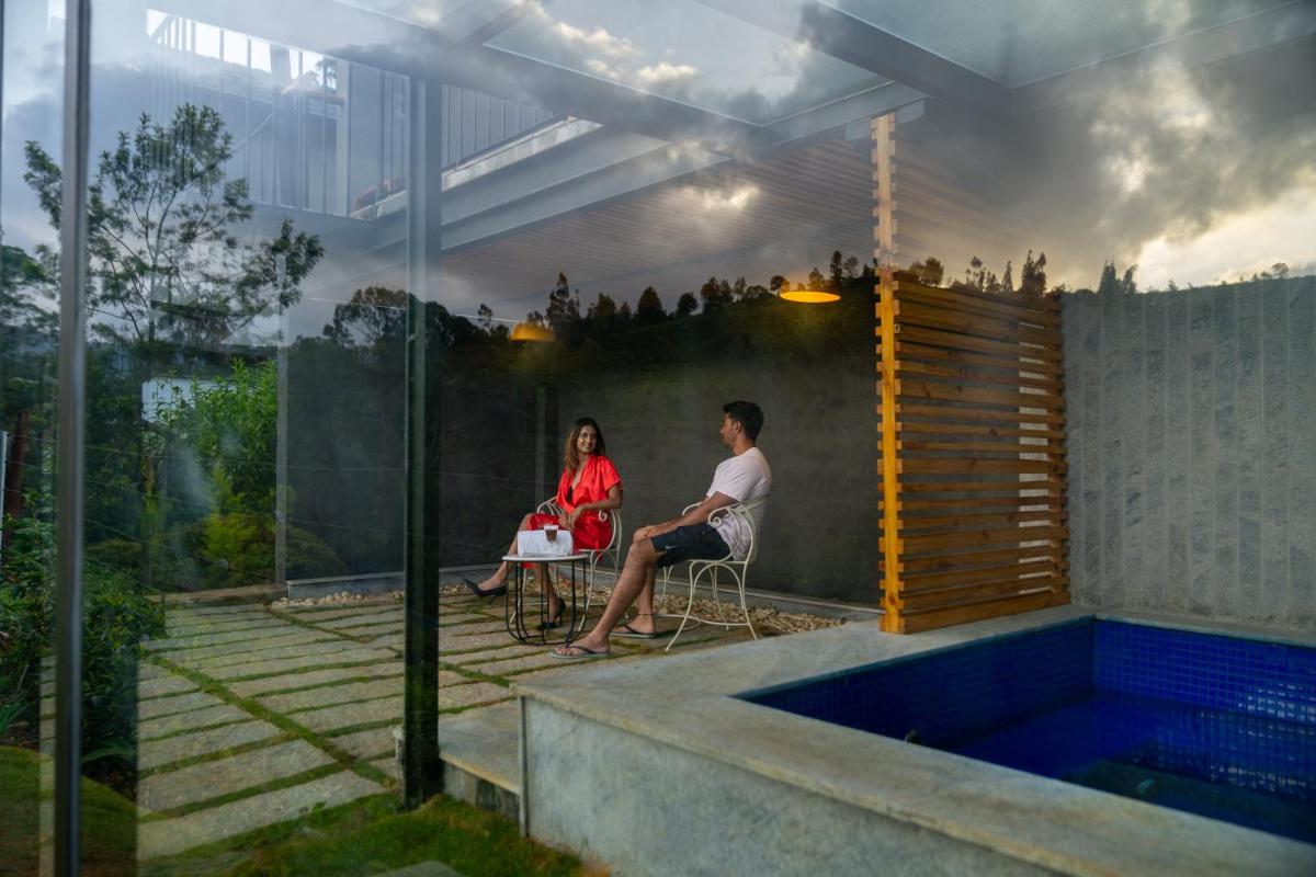 a man and a woman sitting on a chair next to a swimming pool at WelcomHeritage Ayatana Ooty in Ooty