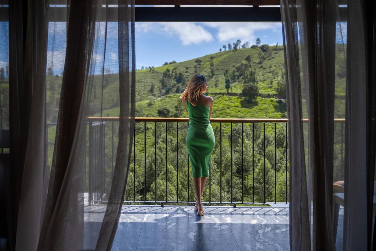 a woman in a green dress standing on a balcony at WelcomHeritage Ayatana Ooty in Ooty