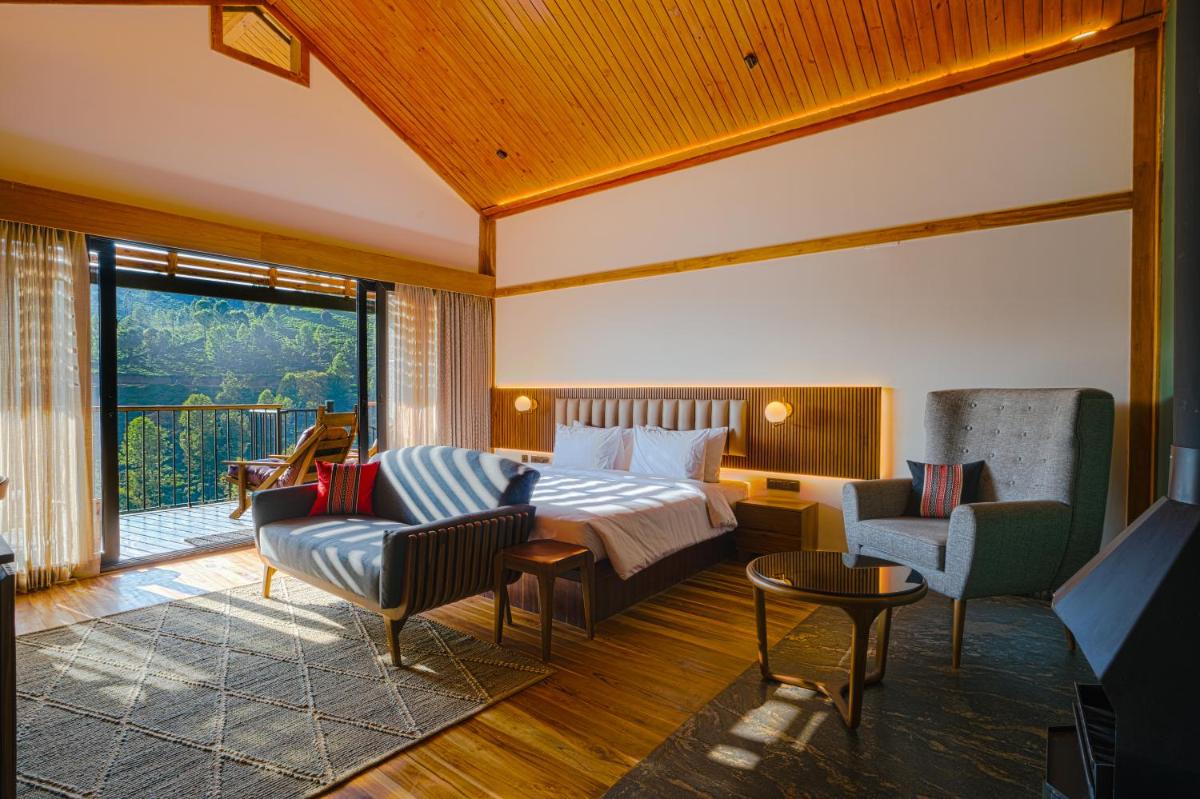 a hotel room with a bed and a couch and chairs at WelcomHeritage Ayatana Ooty in Ooty