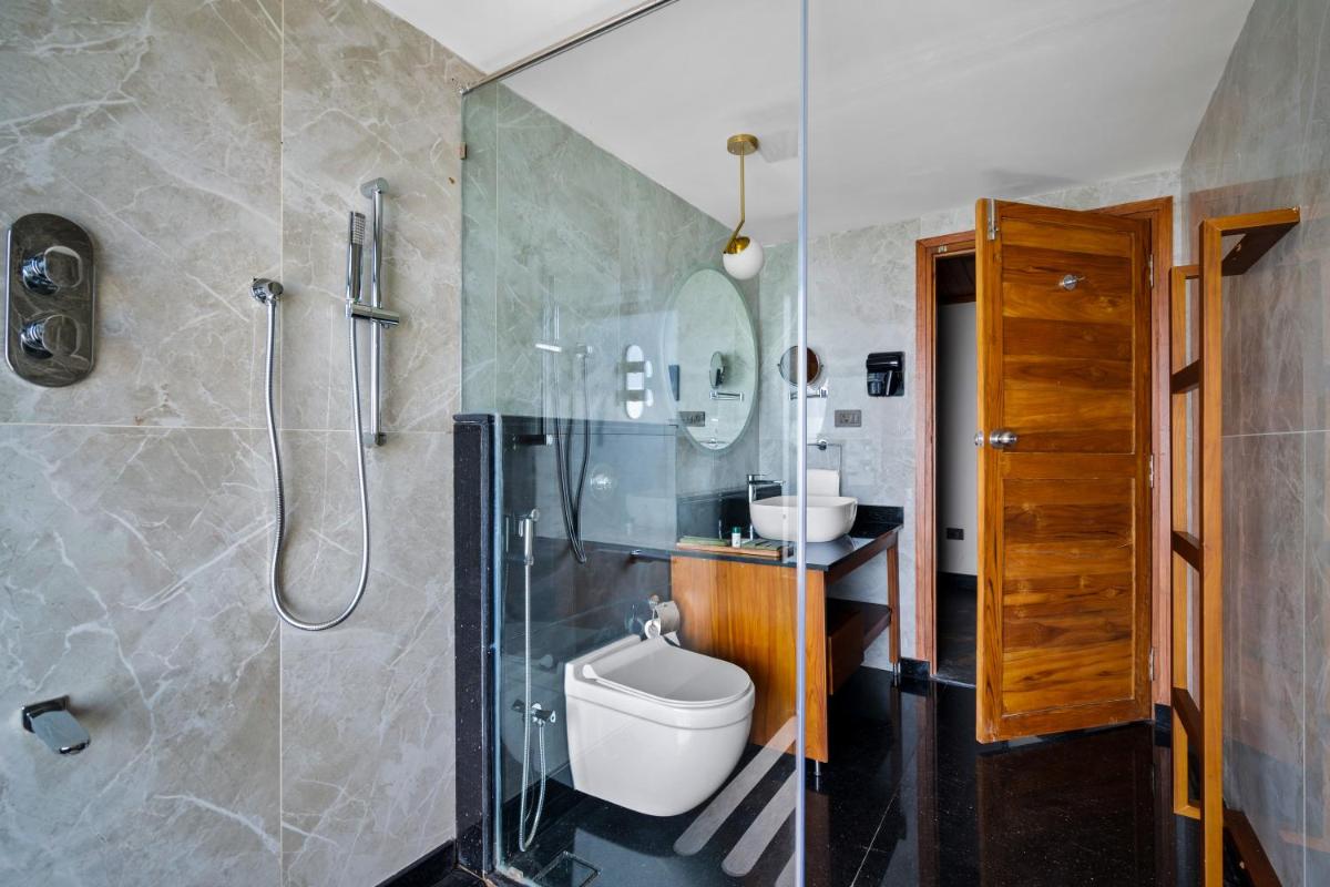 a bathroom with a shower and a toilet and a sink at WelcomHeritage Ayatana Ooty in Ooty