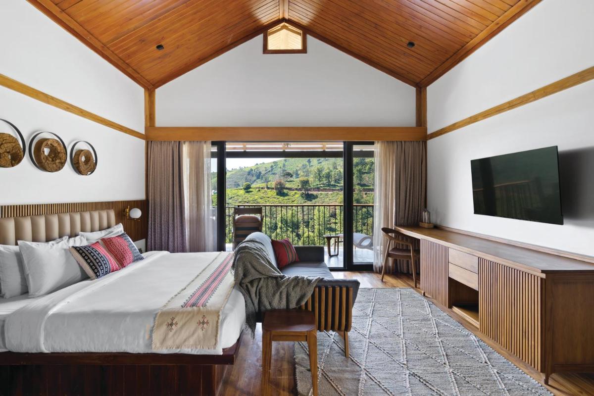 a bedroom with a large bed and a flat screen tv at WelcomHeritage Ayatana Ooty in Ooty