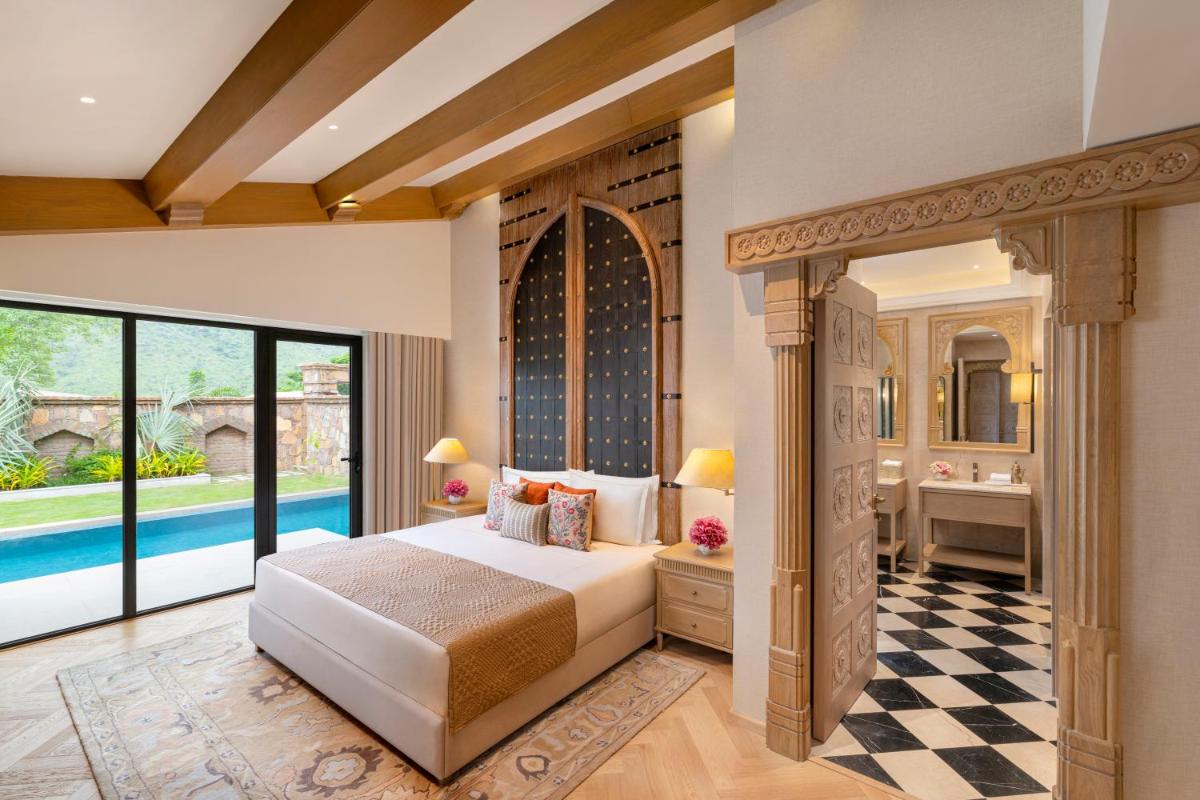 a bedroom with a bed and a bathroom with a pool at Taj Aravali Resort & Spa Udaipur in Udaipur