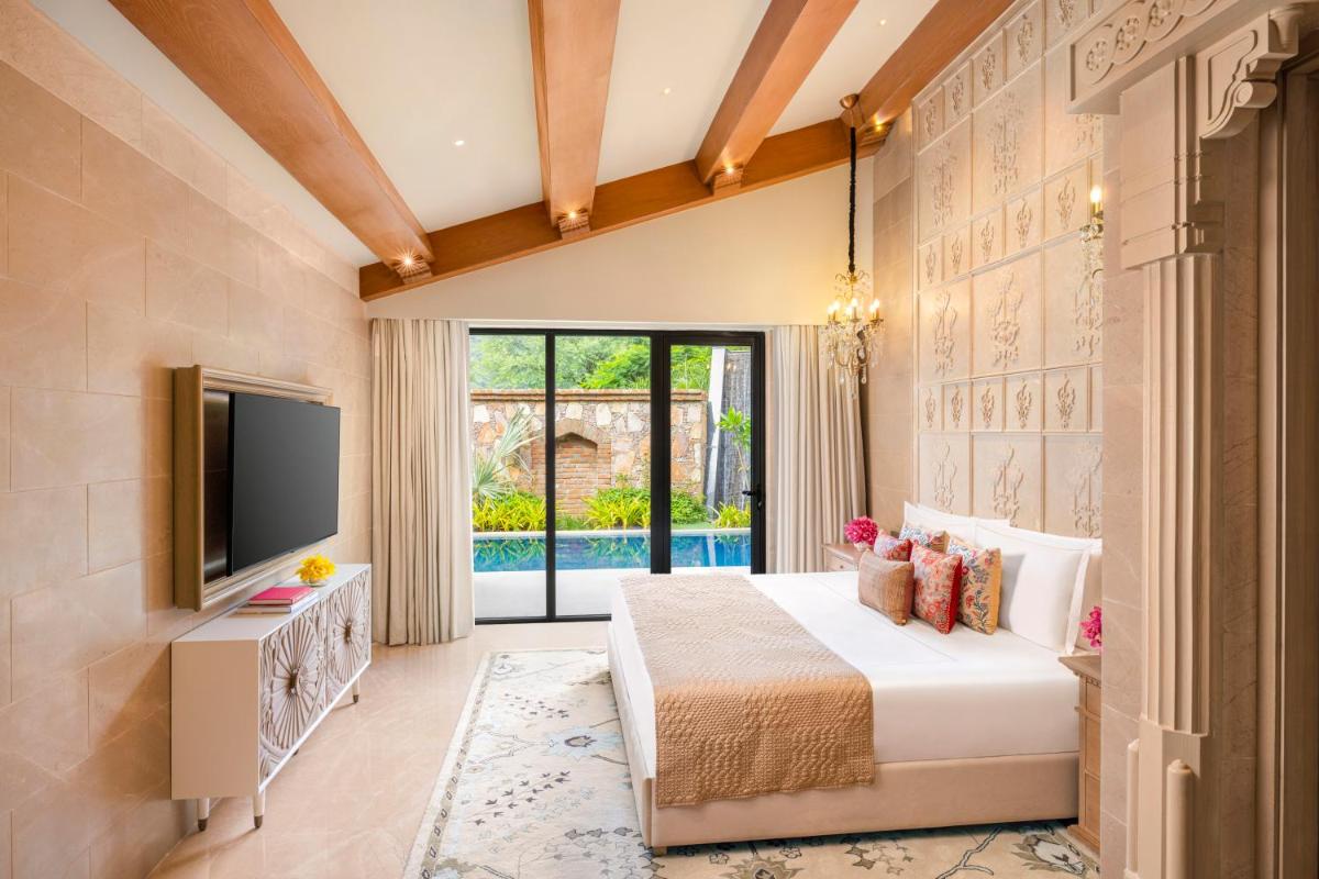 a bedroom with a bed and a tv and a window at Taj Aravali Resort & Spa Udaipur in Udaipur