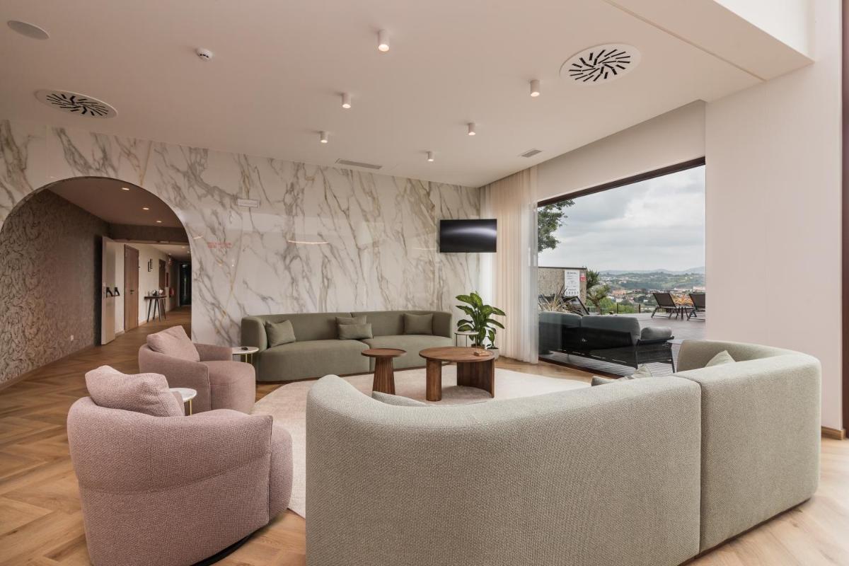 uma sala de estar com um sofá, cadeiras e uma TV em Haven Nature Hotel & Villas na Batalha