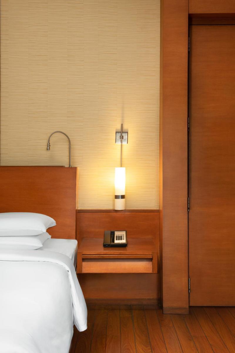 a bedroom with a bed and a clock on a night stand at Hyatt Pune in Pune