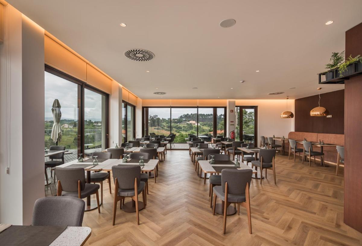 um restaurante com mesas e cadeiras e grandes janelas em Haven Nature Hotel & Villas na Batalha