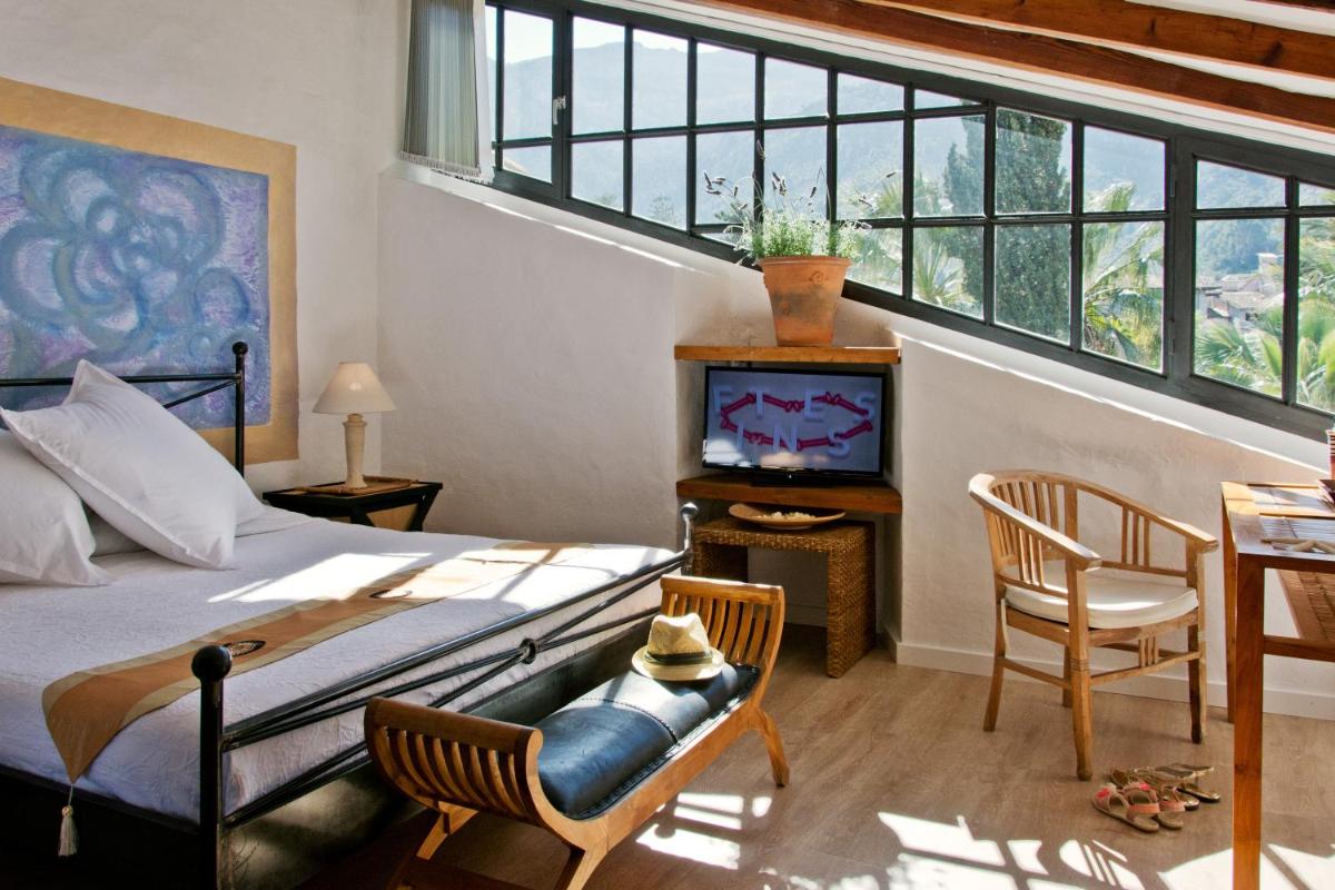 Un dormitorio con una cama, un televisor y una mesa. en Hotel Can Roses, en Sóller