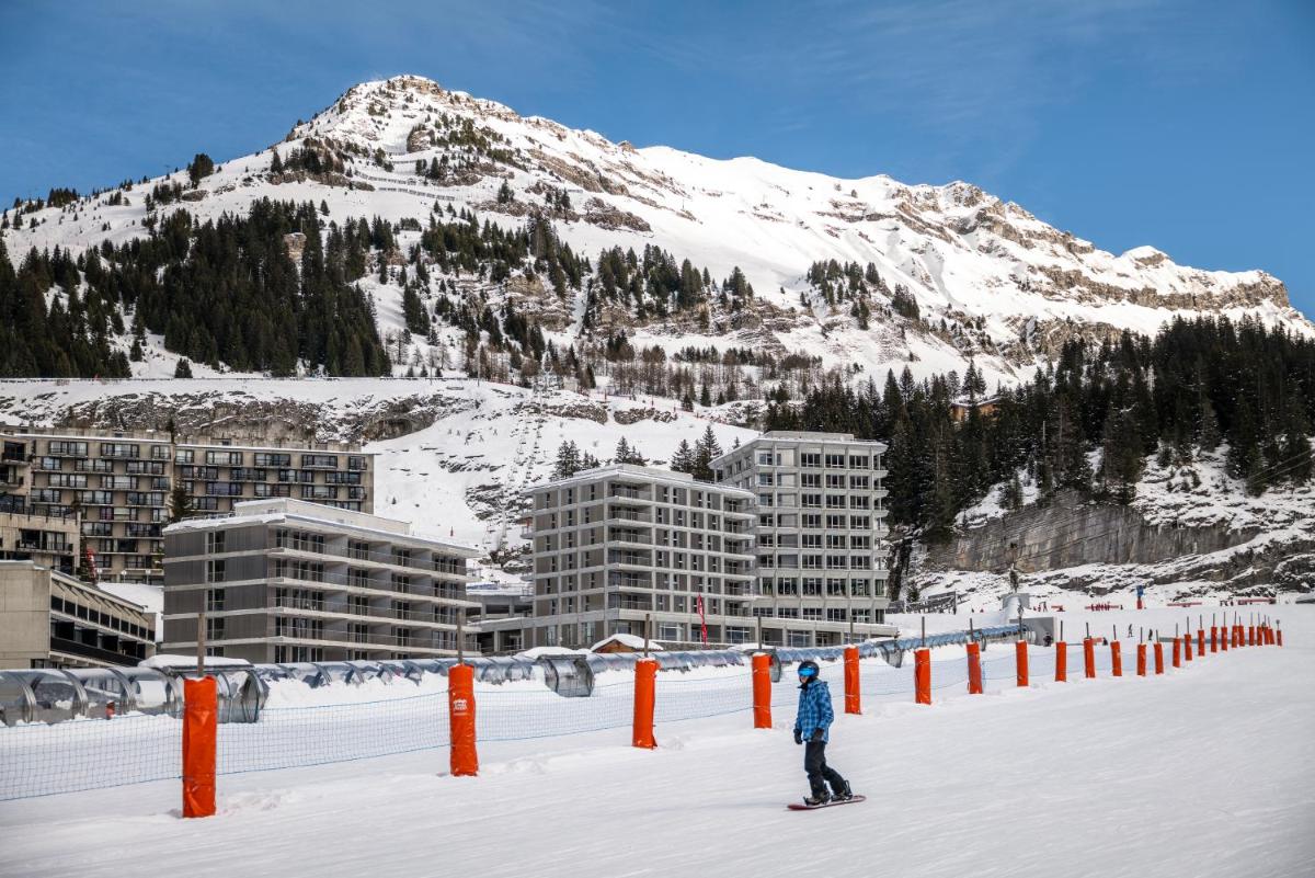 une personne sur un snowboard dans la neige devant une montagne dans l'établissement MGM Hôtels & Résidences - Hôtel Alhéna, à Flaine