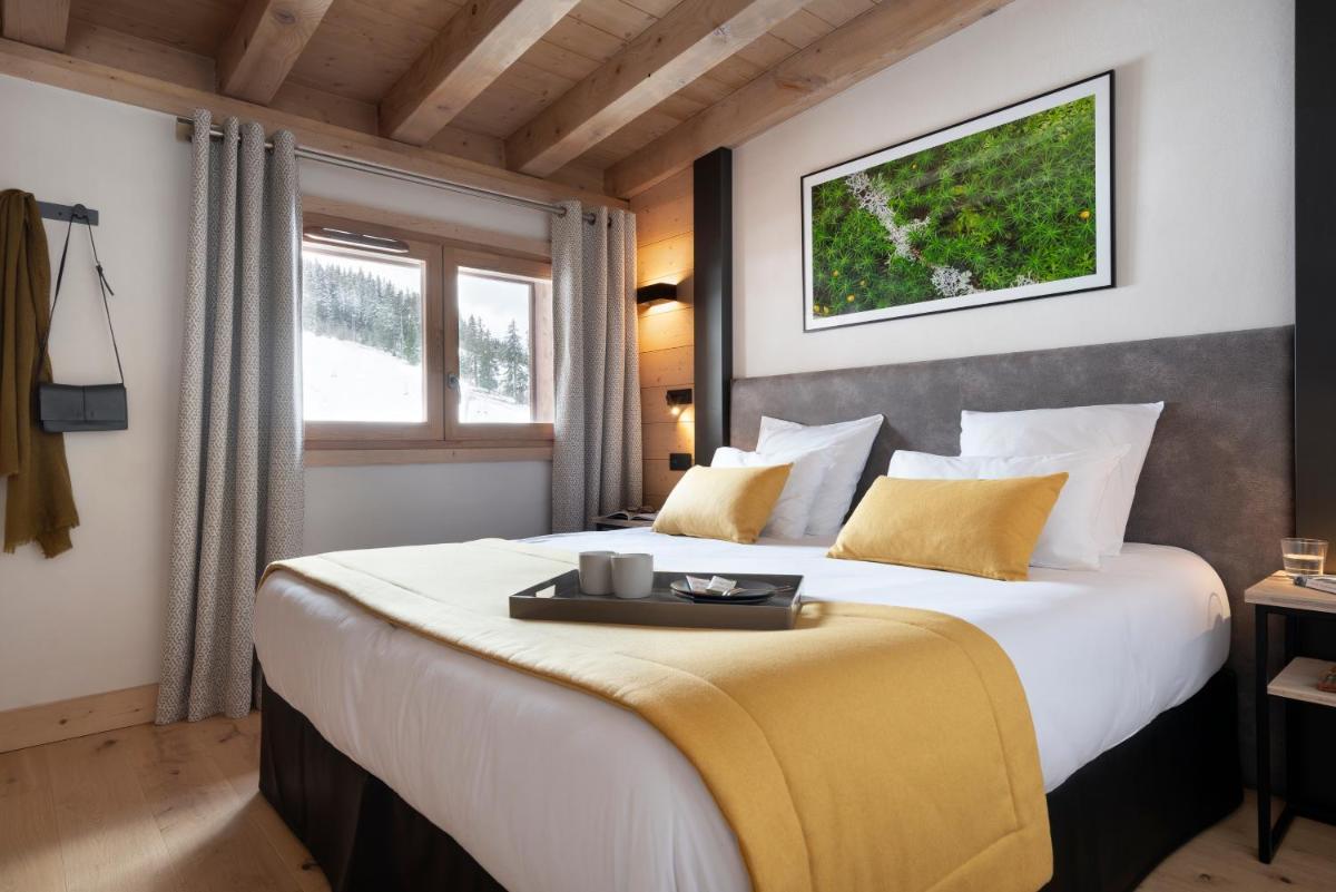 - une chambre avec un grand lit et un plateau dans l'établissement MGM Hôtels & Résidences - Résidence Le Hameau de l'Ours, à Manigod