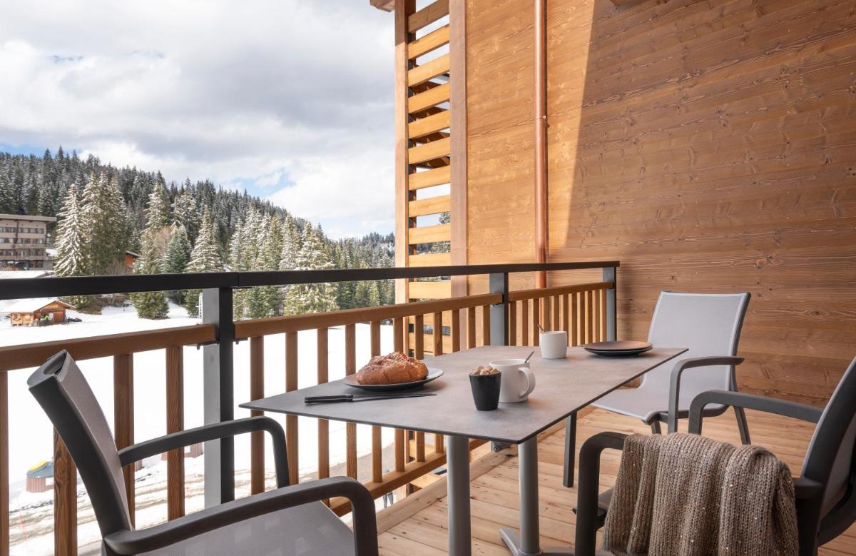 une table et des chaises sur un balcon avec vue dans l'établissement MGM Hôtels & Résidences - Résidence Le Hameau de l'Ours, à Manigod