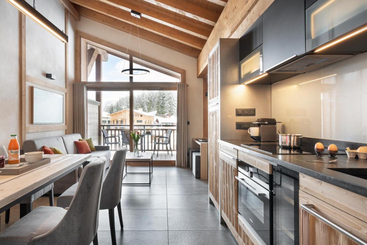 une cuisine avec un comptoir et une table avec des chaises dans l'établissement MGM Hôtels & Résidences - Résidence Le Hameau de l'Ours, à Manigod 59 autres photos