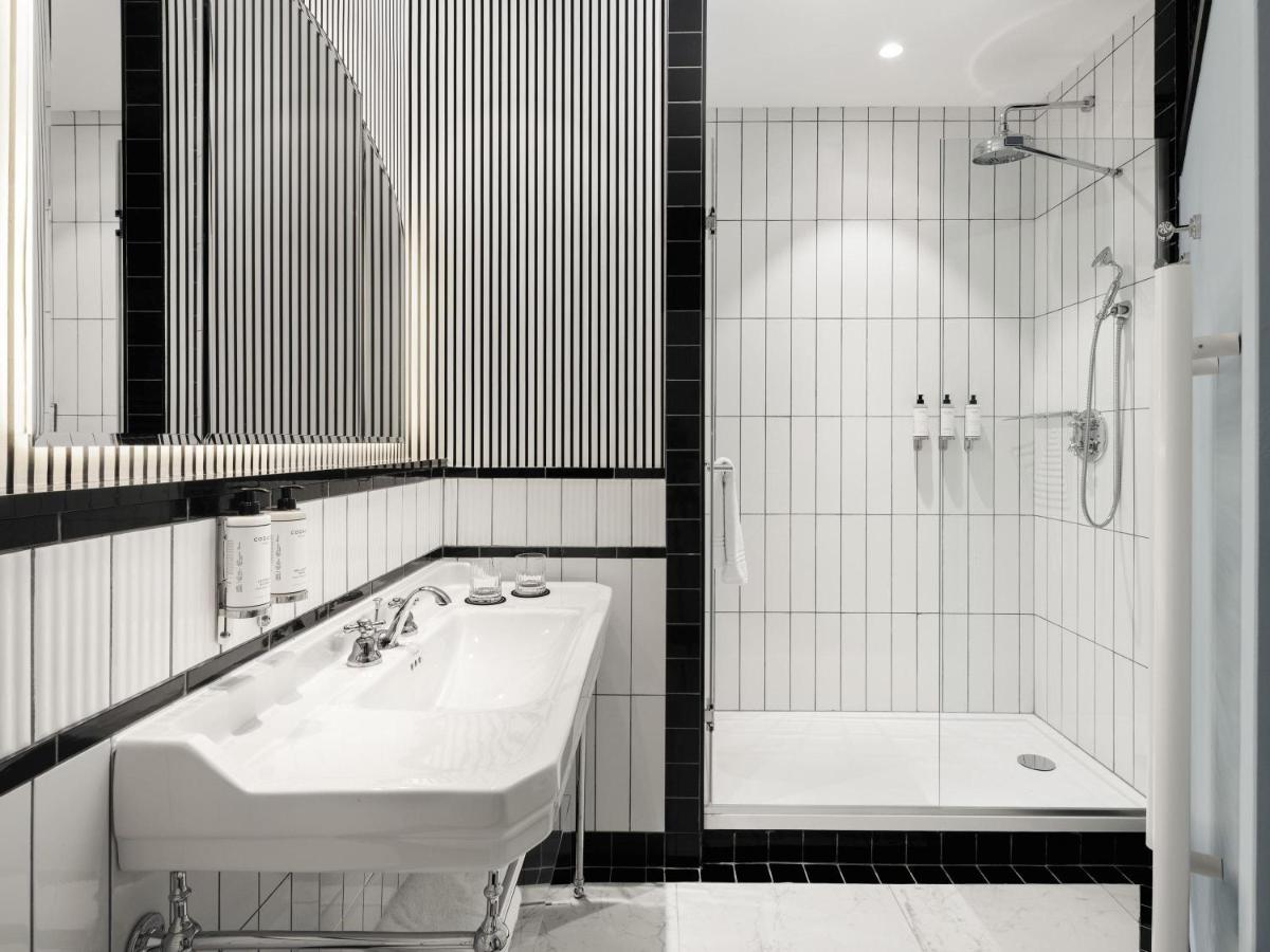 une salle de bain en noir et blanc avec un lavabo et une douche dans l'établissement The 1932 Hotel & Spa Cap d'Antibes - MGallery Collection, à Juan-les-Pins
