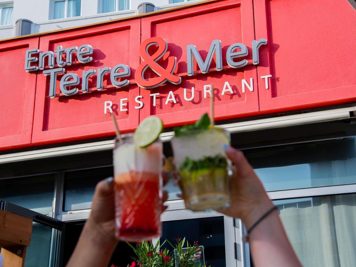 une personne tenant deux boissons devant un restaurant dans l'établissement ibis La Baule Pornichet Plage, à Pornichet